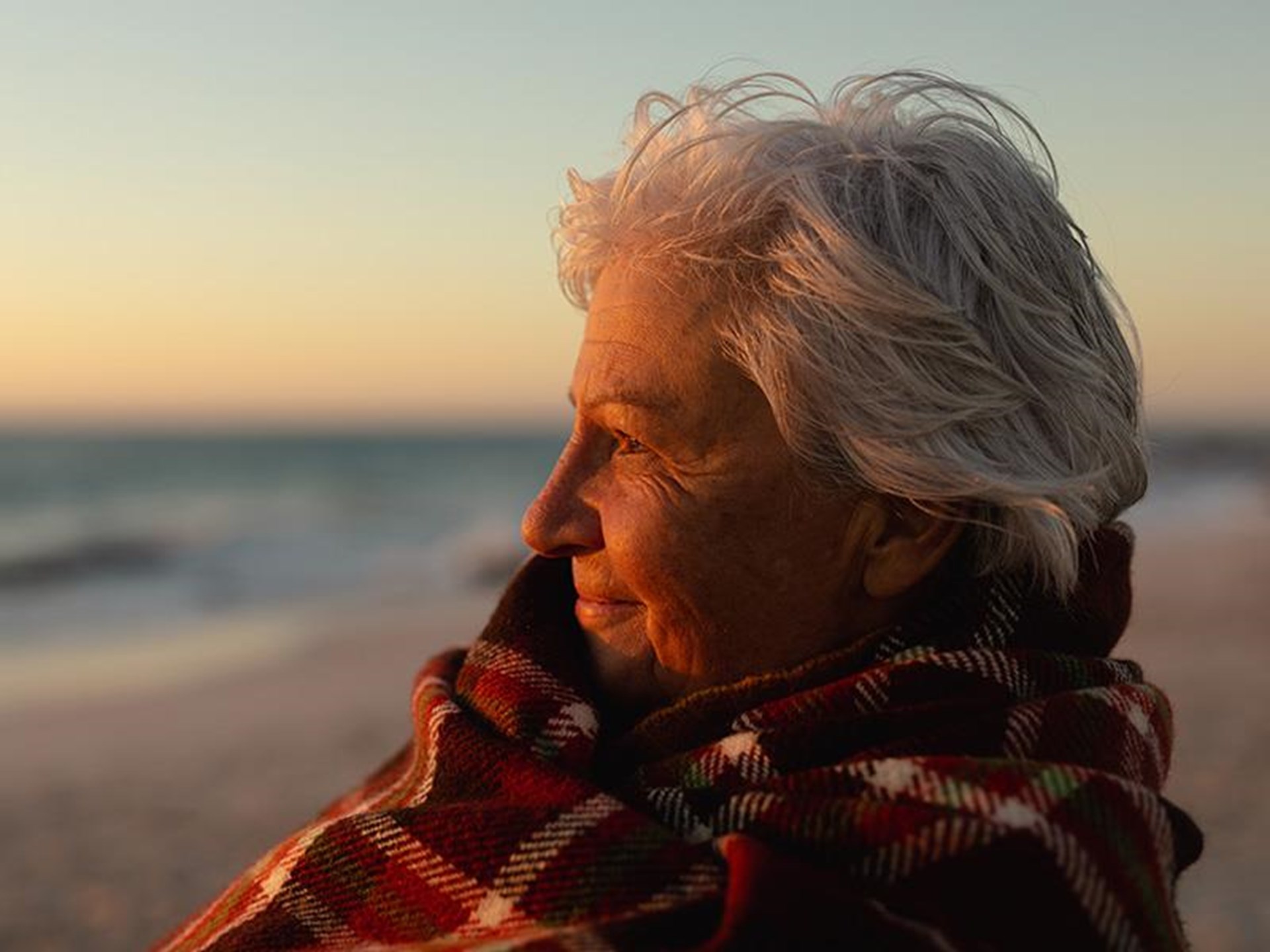 ältere Frau am Strand bei Sonnenuntergang
