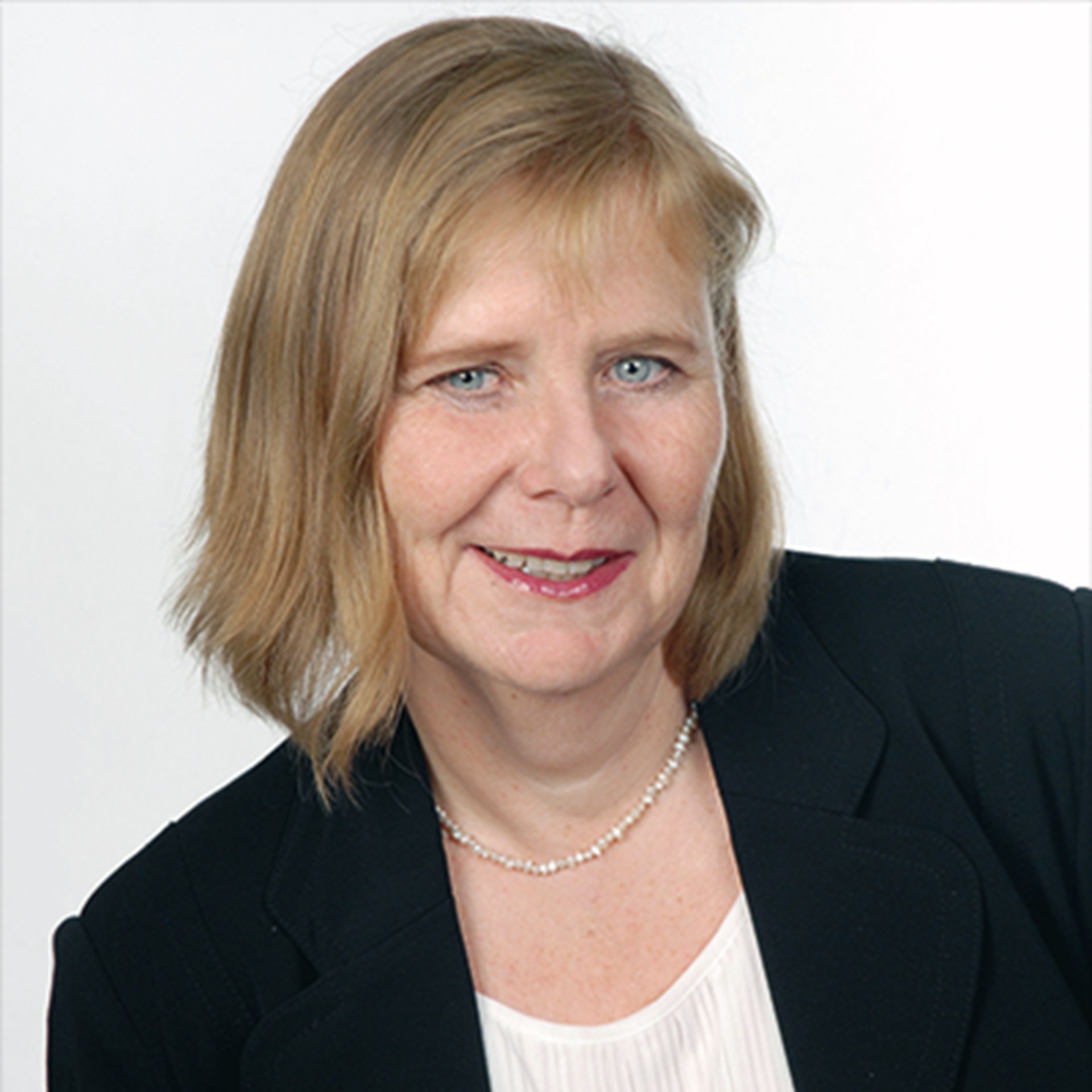 Lächelnde Frau mit blonden Haaren, die in weißes T-Shirt und eine schwarze Anzugjacke trägt