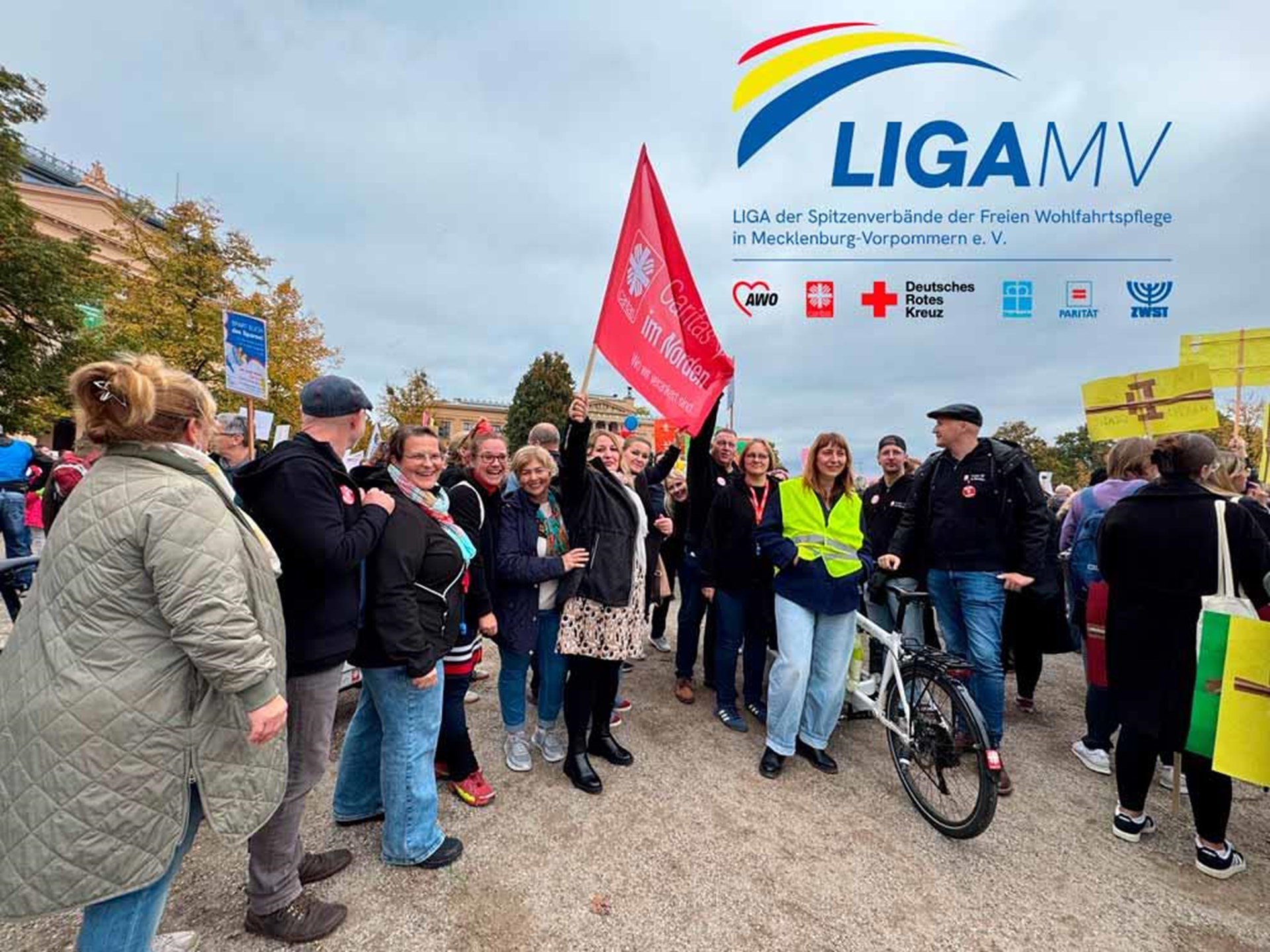Demonstrierende mit Caritas-Fahne bei der Demonstration Bleibt Sozial mit dem Logo der LIGA M-V