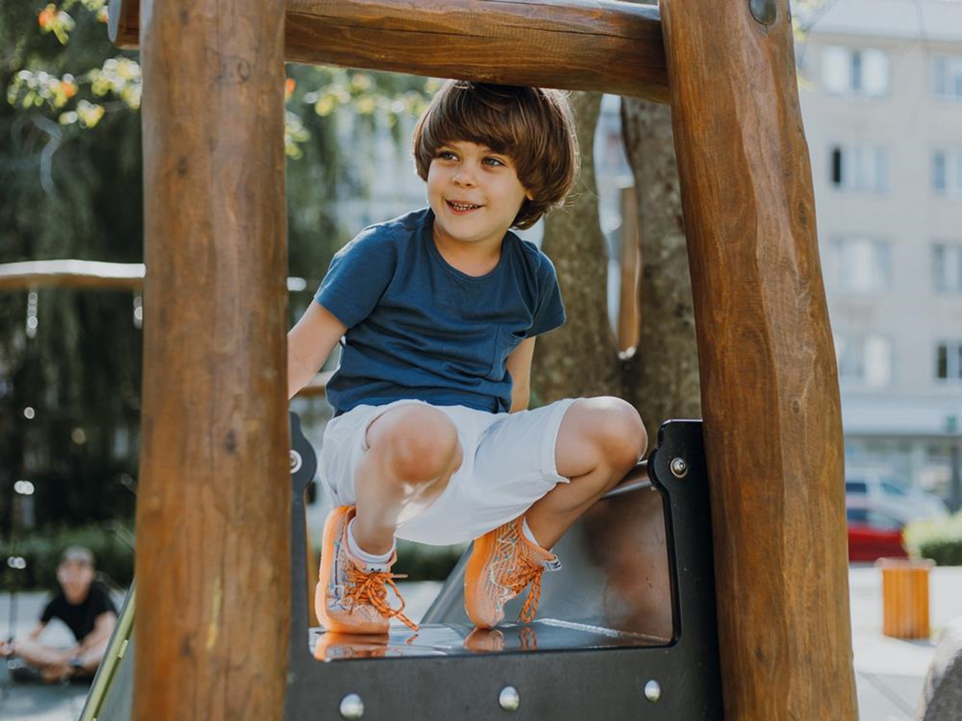 Ein Junge, 9 Jahre alt, hockt in einem Holzhaus auf dem Spielplatz einer Kita