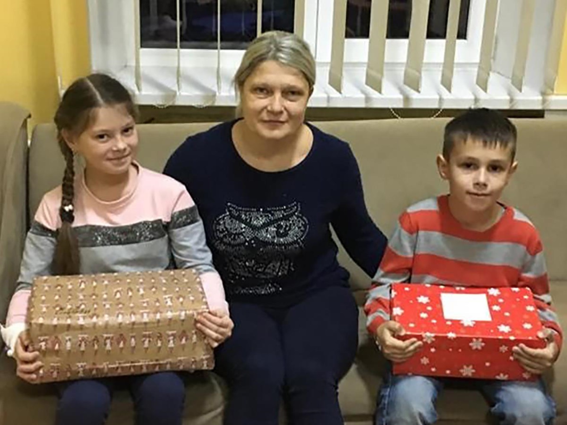 Foto einer ukrainischen Mutter mit zwei Kindern, die Weihnachtsgeschenke halten